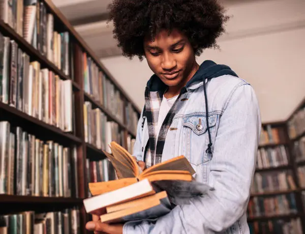 A black student looking at books in a library