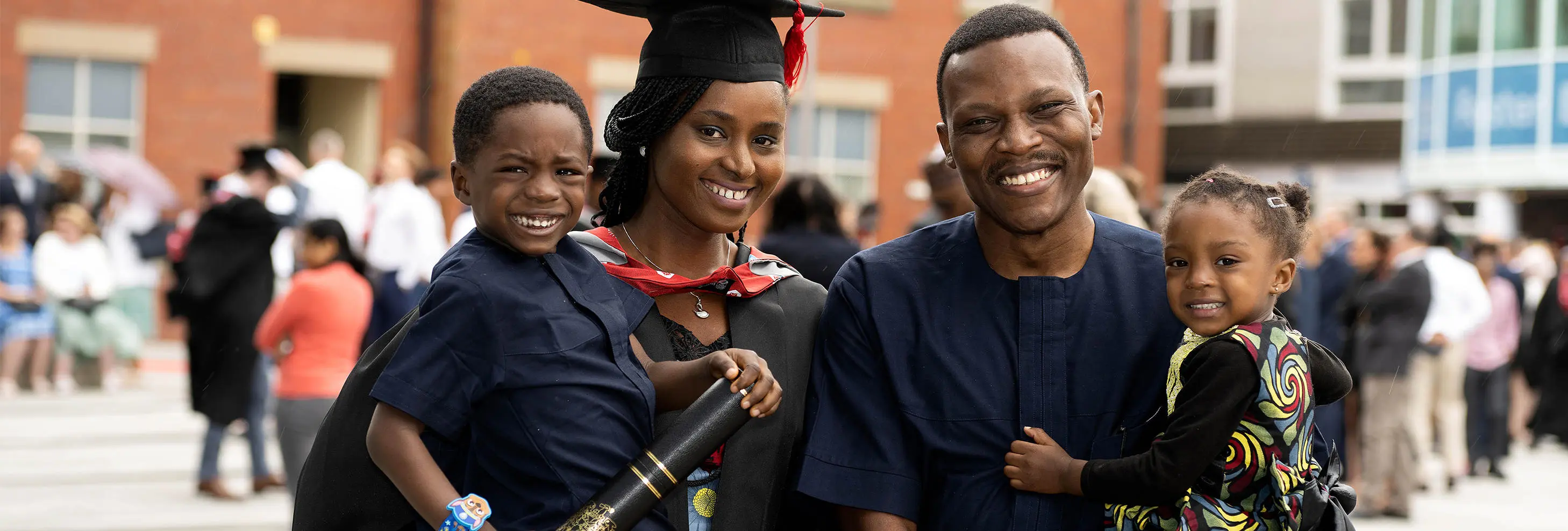 A boy smiling, a woman wearing an academic cap and gown, a man smiling and a girl smiling