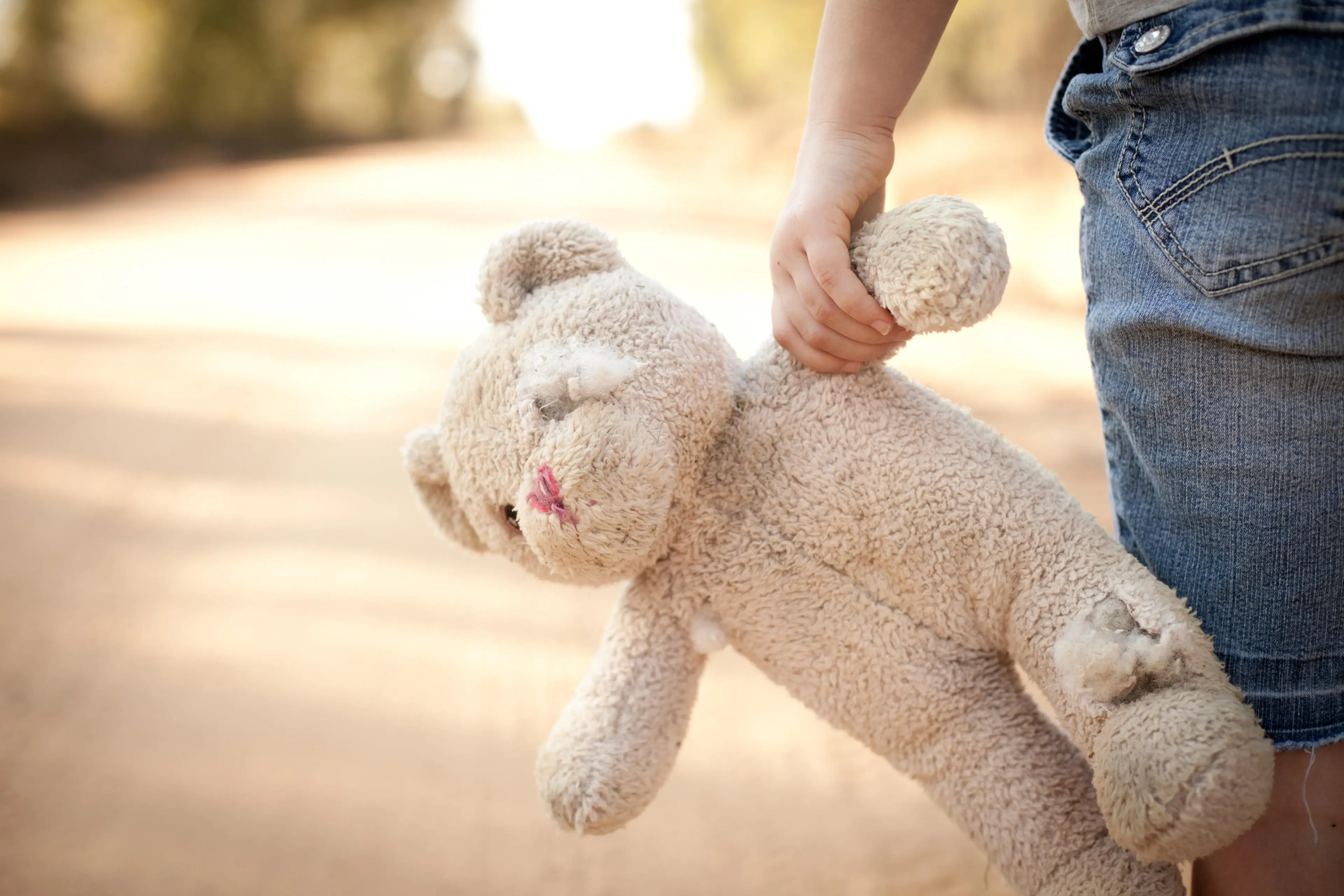 Child holding arm of teddy bear