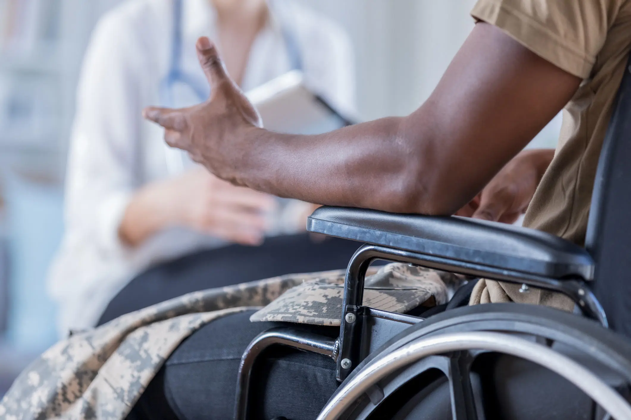 A person sat in a wheelchair talking to a medical professional