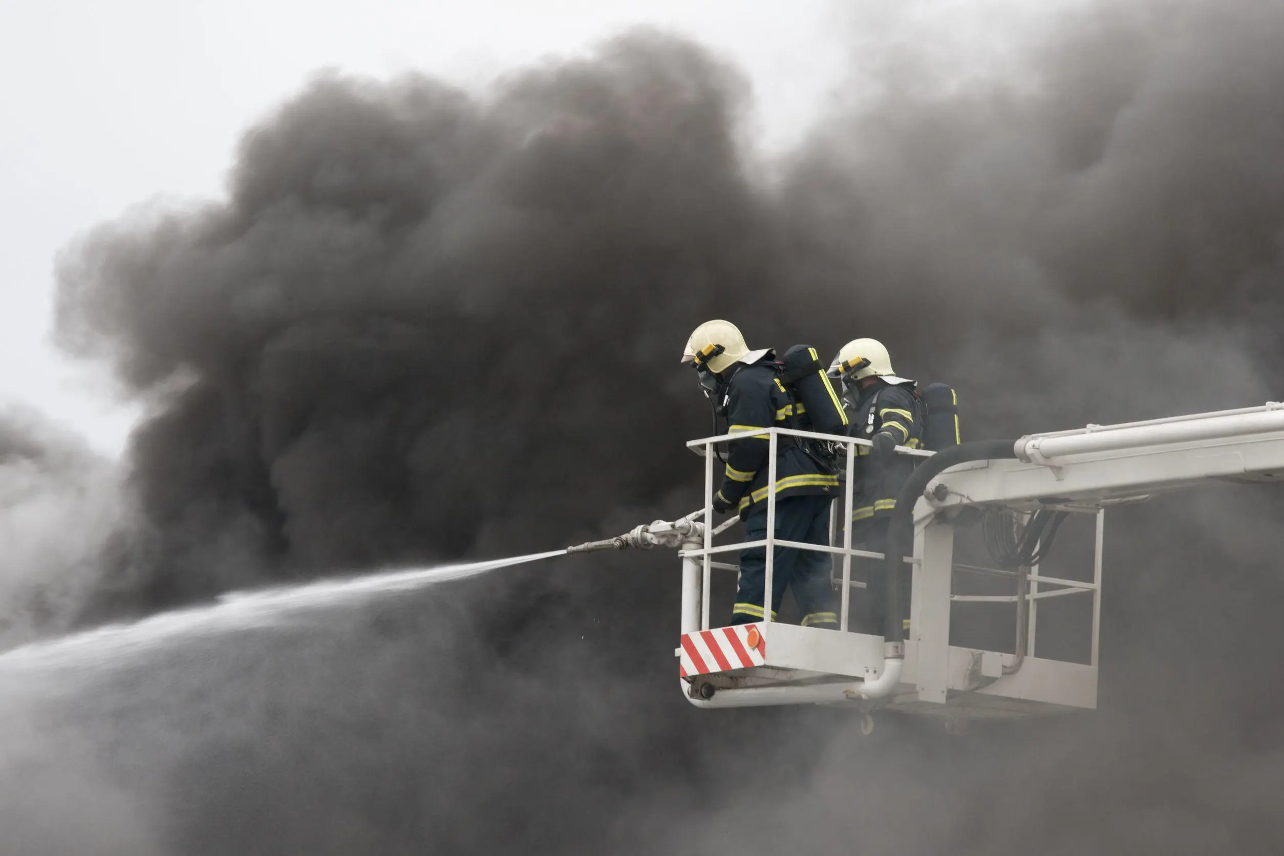 Fire fighters putting out a fire surrounded by smoke