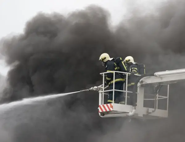 Fire fighters putting out a fire surrounded by smoke