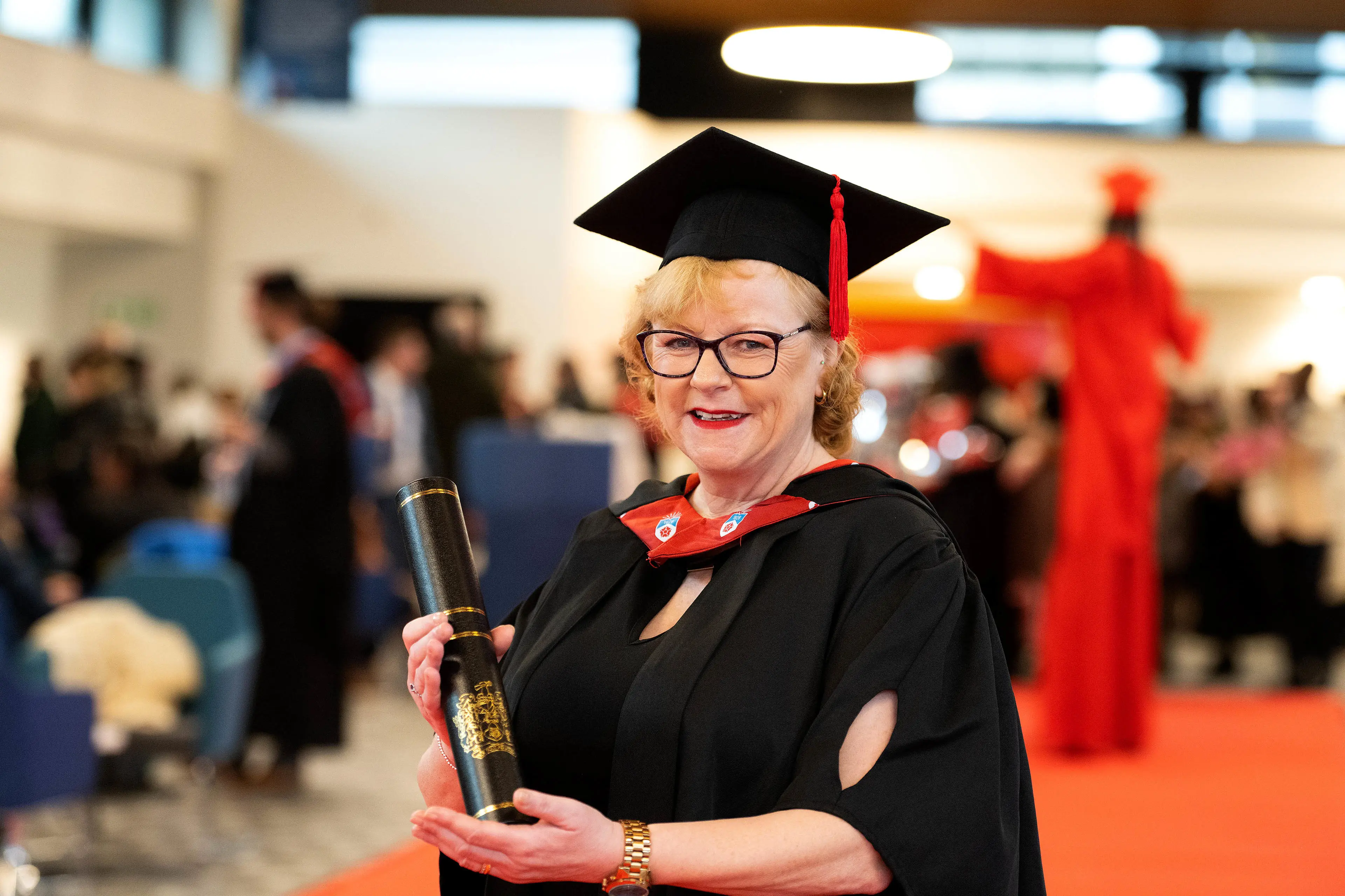 Michelle Lomas dressed in a cap and gown and holding a scroll