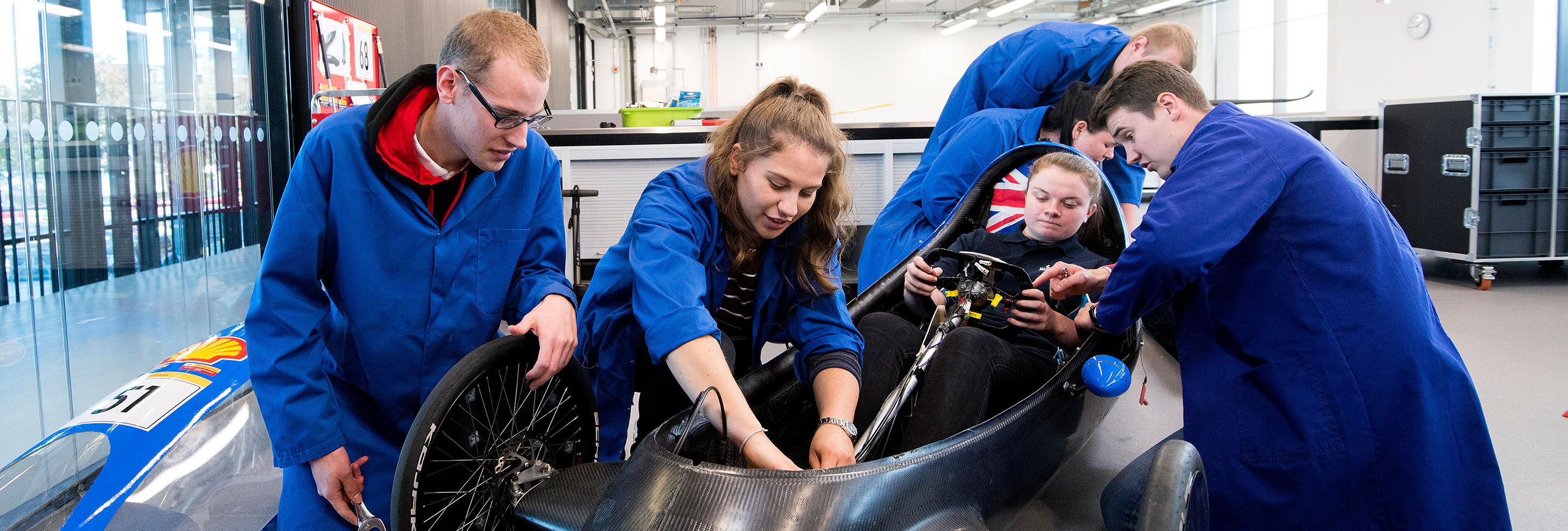 Male and female students working on a motor racing car