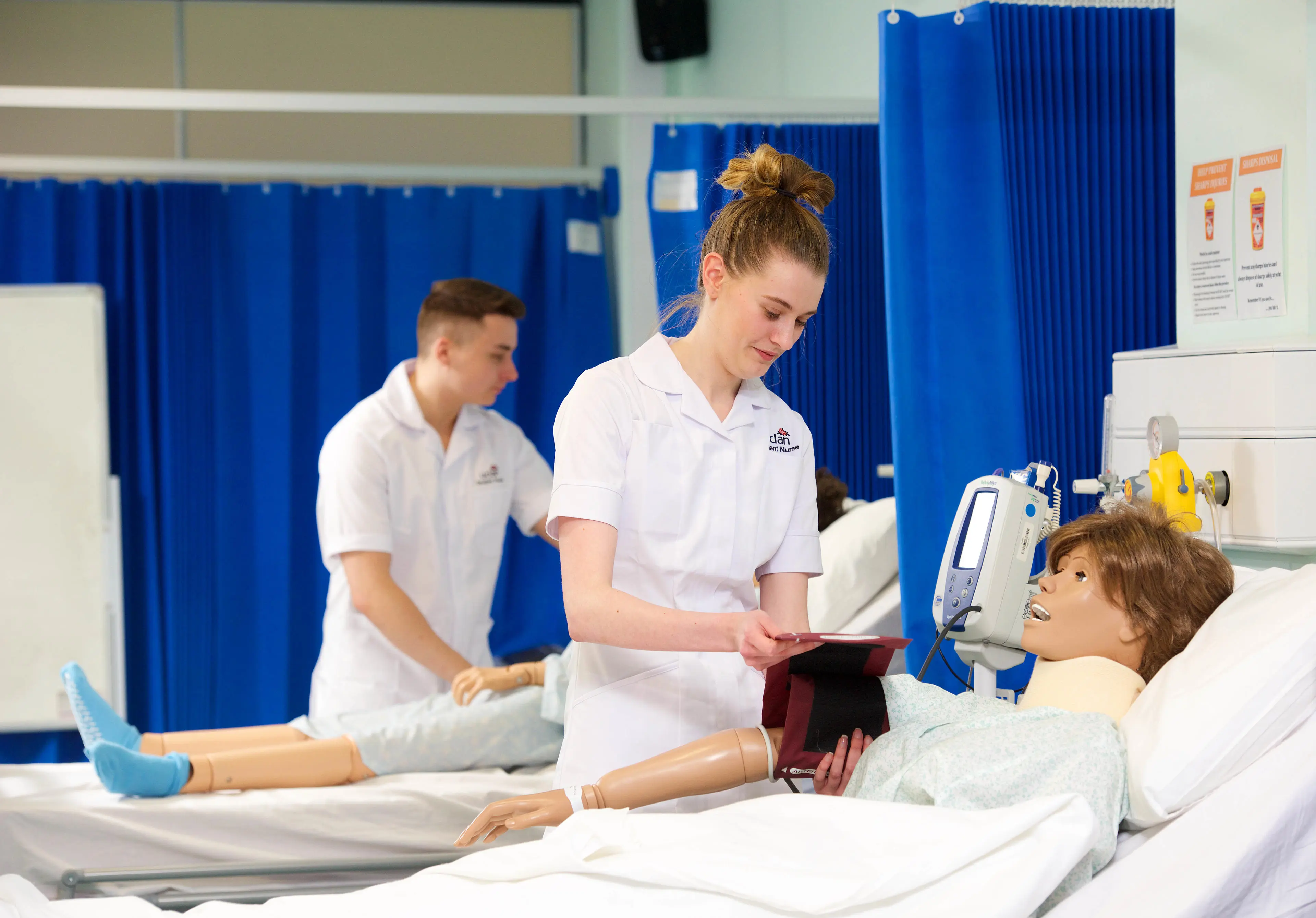 Two student nurses training with medical dummies.