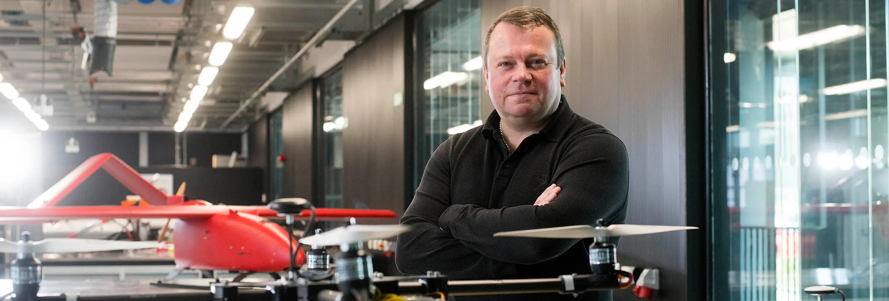 Head and shoulders photo of Professor Darren Ansell stood in front of an unmanned aerial vehicle