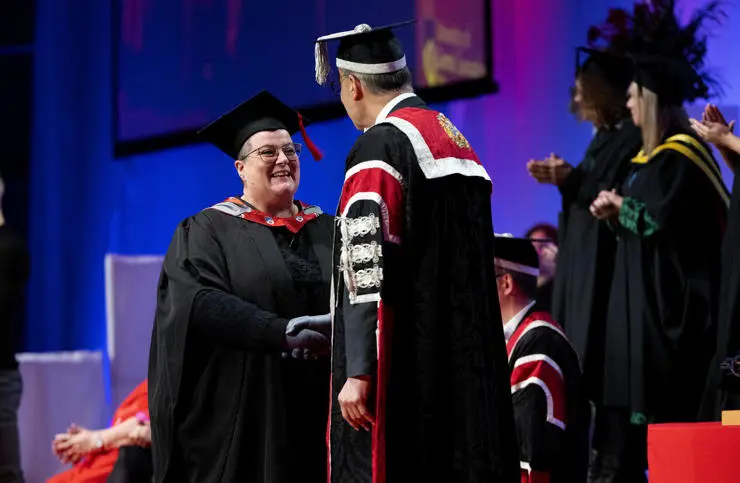 Kerry Clark shaking hands on the graduation stage with Vice-Chancellor Professor Graham Baldwin