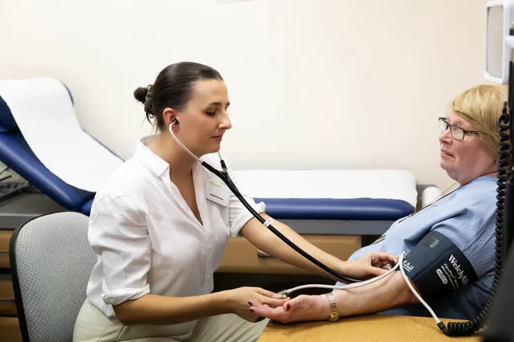 A patient volunteer having her blood pressure taken by a student doctor