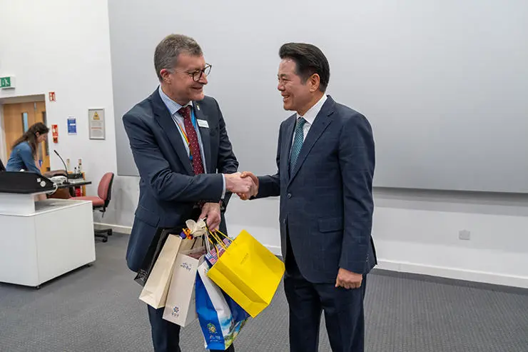 Vice Chancellor Graham Baldwin is presented with gifts in gift bags from South Korea