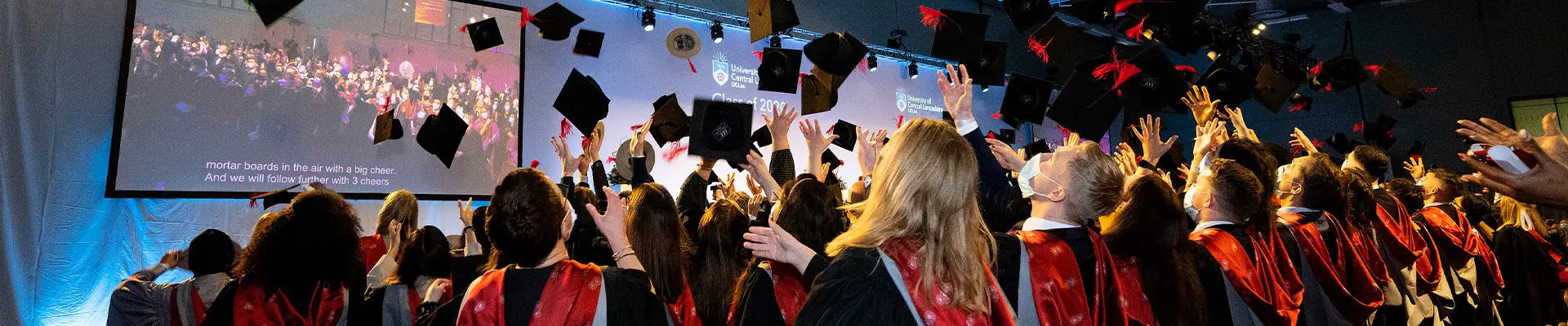 Graduates throwing hats in graduation hall