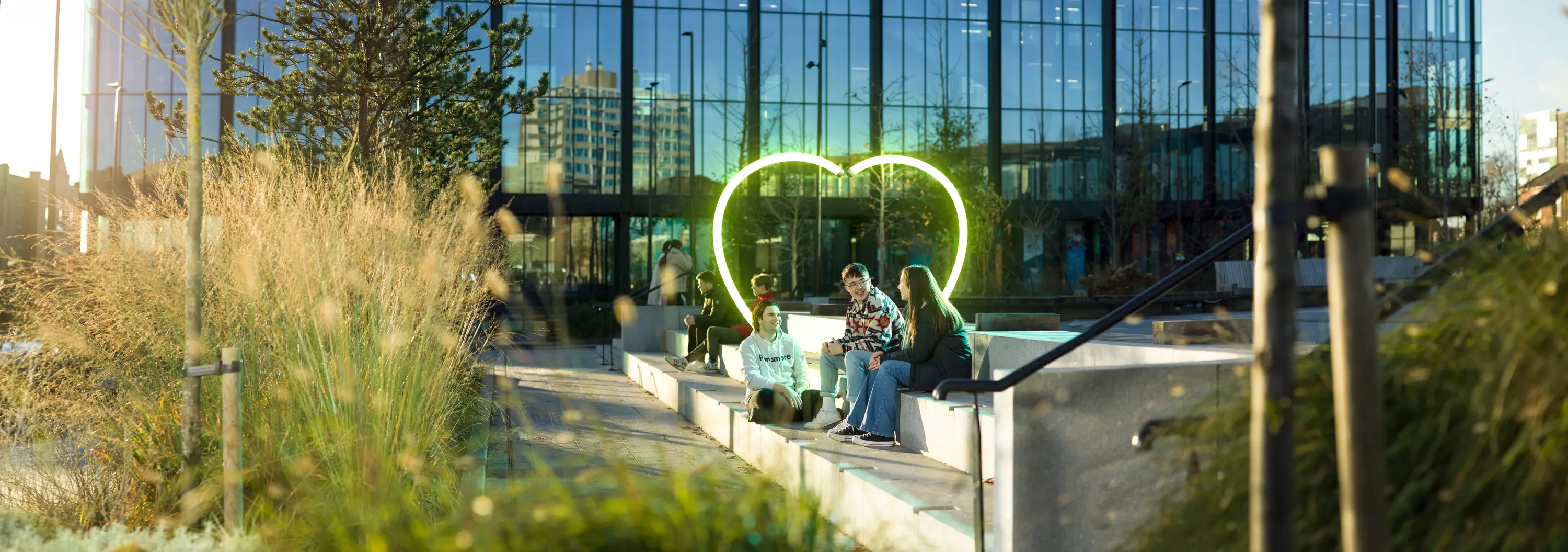 students sat on the steps outside the engineering innovation centre illuminated by a heart